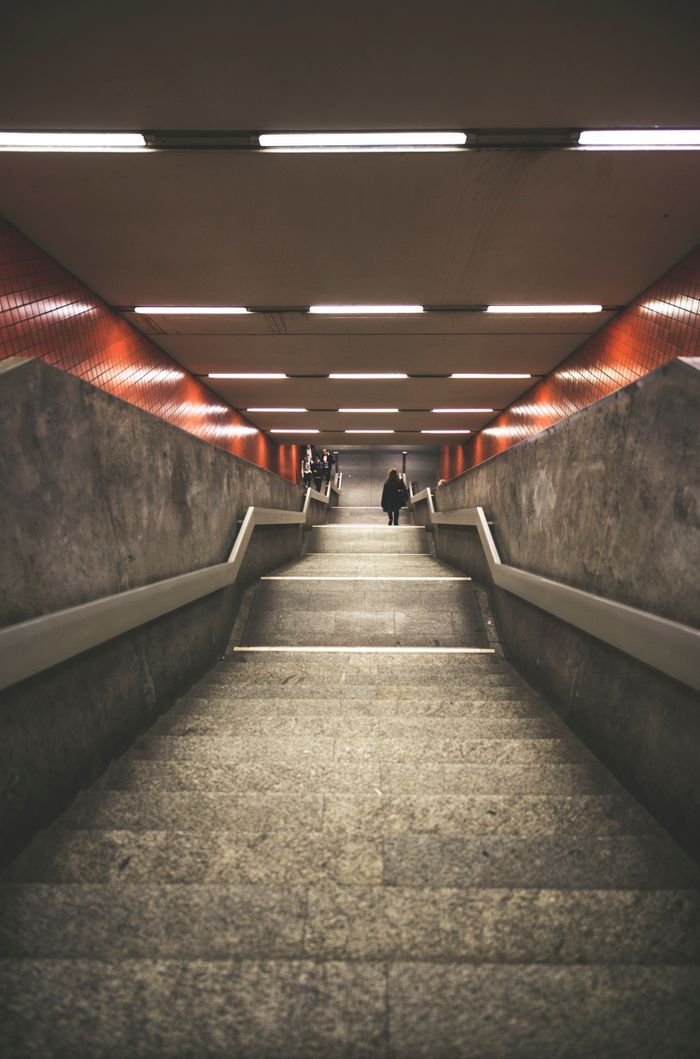 Wide-angle view of a subway staircase with dramatic lighting and architecture.